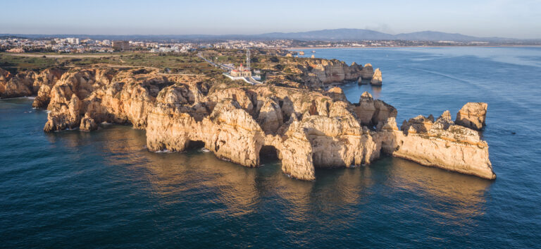 Acantilados de piedra dorada con cuevas marinas en la costa del Algarve, Portugal, junto a aguas azul turquesa