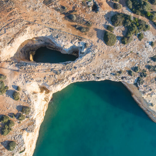 Vista aérea de acantilados calcáreos del Algarve con cuevas marinas y aguas turquesas