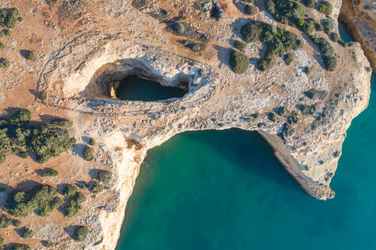 Vista aérea de acantilados calcáreos del Algarve con cuevas marinas y aguas turquesas