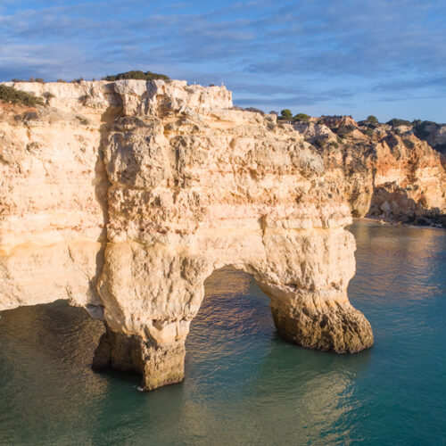 Acantilados de piedra caliza con arco natural junto a aguas turquesas del Algarve