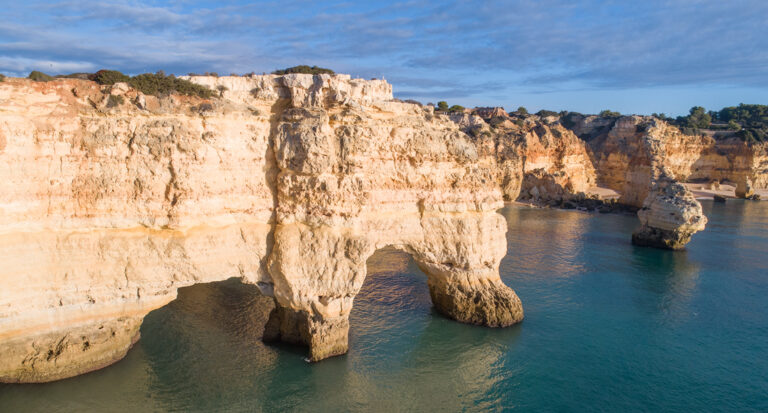 Acantilados de piedra caliza con arco natural junto a aguas turquesas del Algarve