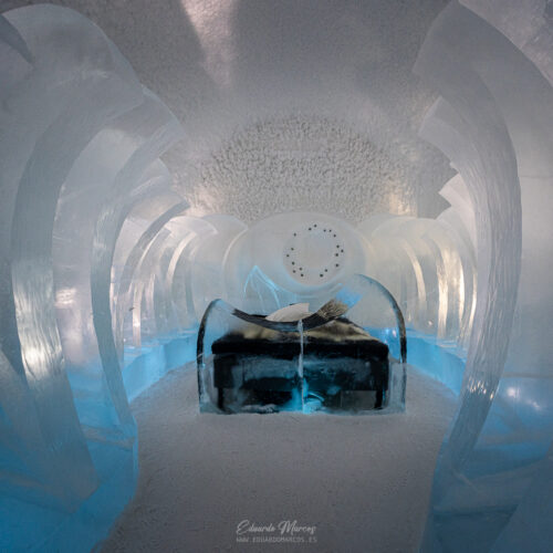 Interior de túnel de hielo azul con estructura de hielo en las paredes y zona de descanso con equipamiento negro al fondo