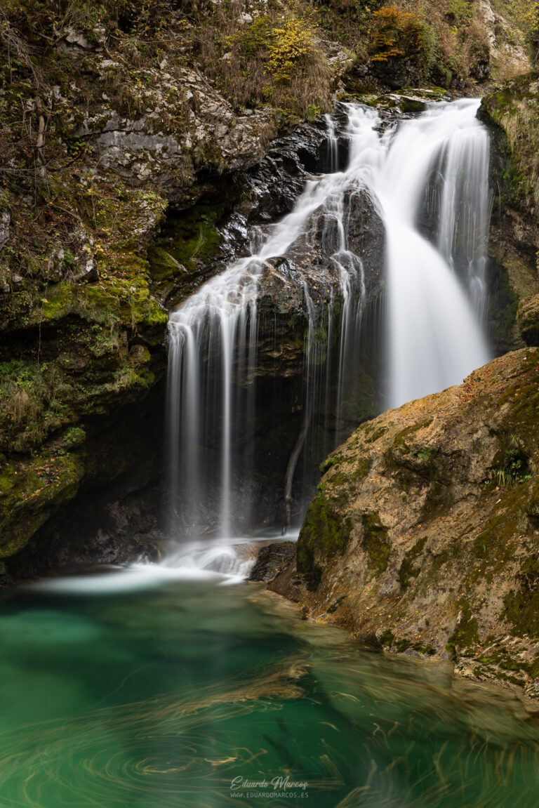 Cascada de aguas blancas en garganta rocosa con piscina turquesa rodeada de musgo y vegetación