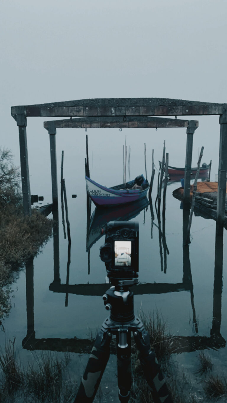 Cámara de película sobre trípode enfocando góndolas tradicionales amarradas en la brumosa ría de Aveiro