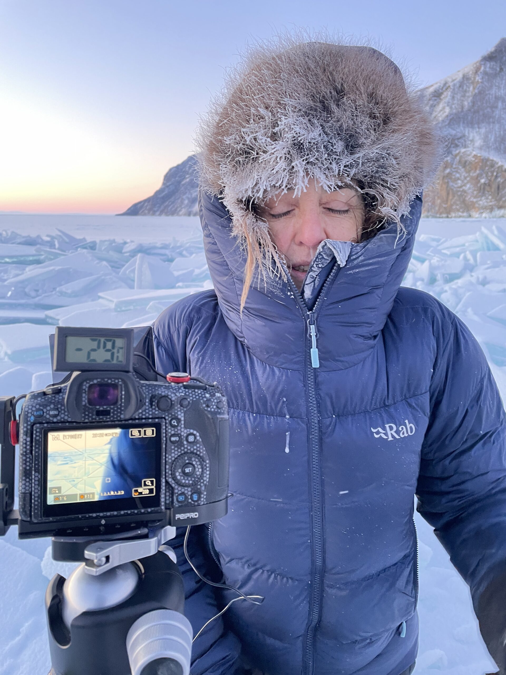 Canon camera on a tripod with a thermometer reading -29 °C on the ice of Lake Baikal