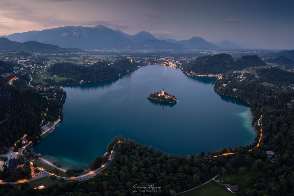 Lago Bled al atardecer con iglesia en isla, bosques y montañas de fondo en Eslovenia
