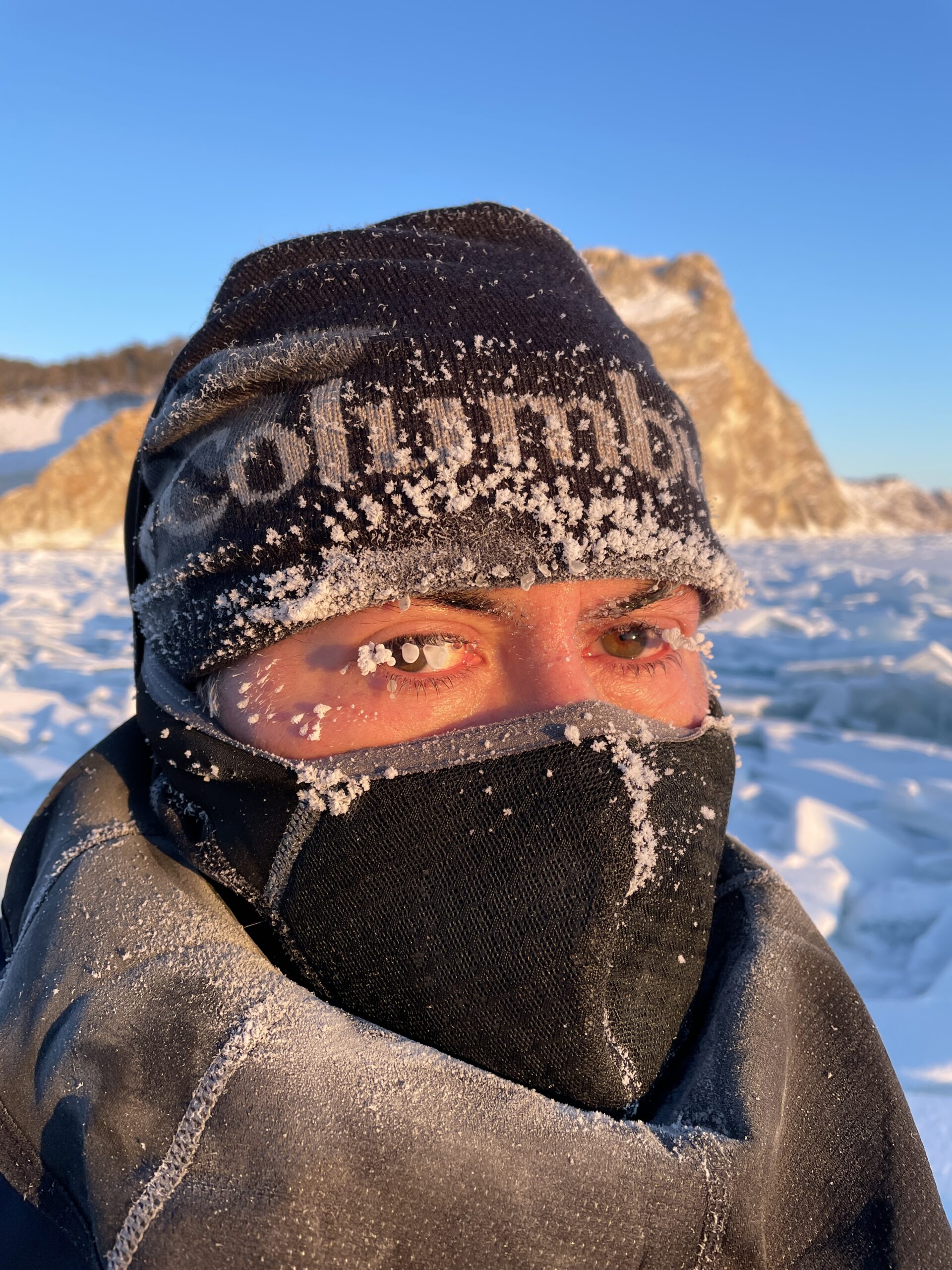 Face covered by hat and neck gaiter, frozen eyelashes and eyebrows on Lake Baikal