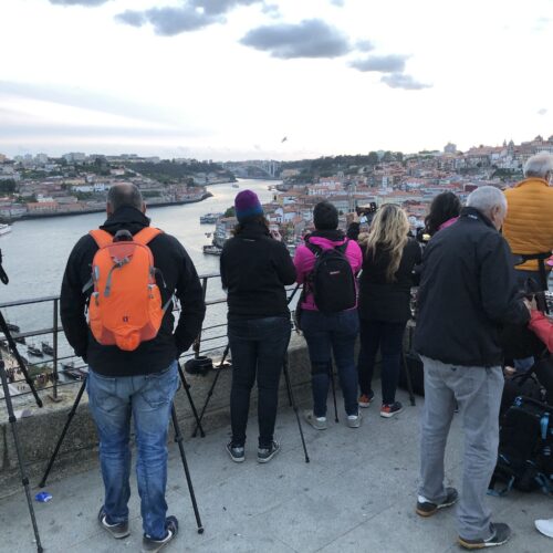 Grupo de turistas observa la Ría de Aveiro desde un mirador, con cámaras y trípodes, vistas de la ciudad y río al fondo