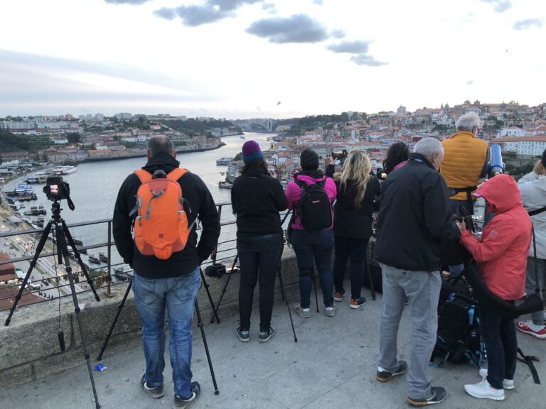 Grupo de turistas observa la Ría de Aveiro desde un mirador, con cámaras y trípodes, vistas de la ciudad y río al fondo
