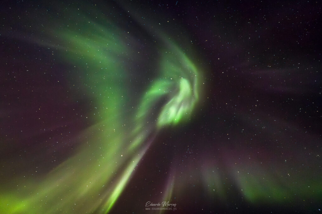 Aurora boreal con cortinas verdes brillantes ondulando en el cielo nocturno estrellado de Abisko